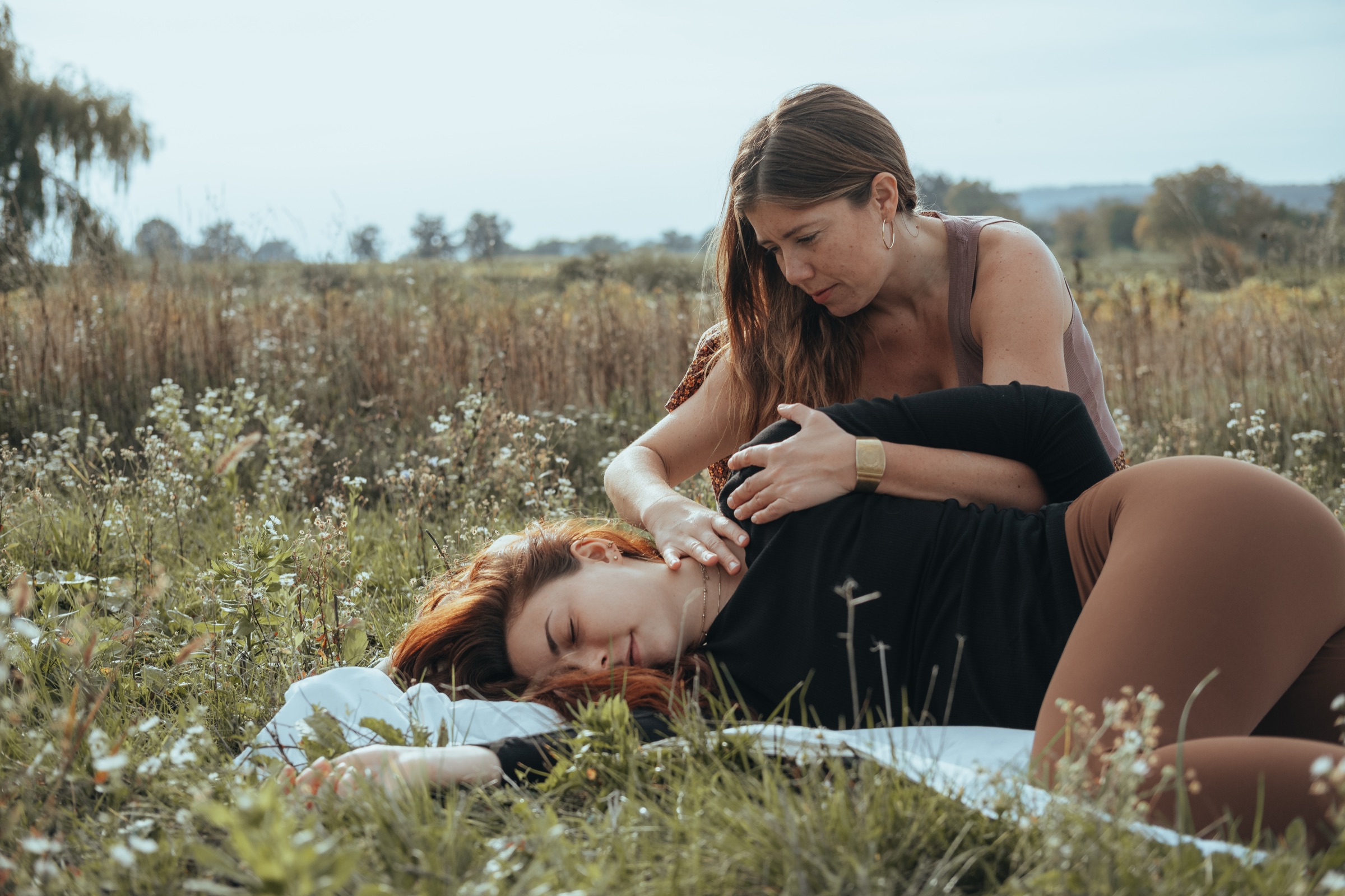 Kathrin supporting a client’s shoulder and neck during an outdoor bodywork session